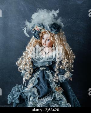 Erstaunlich realistische Vintage Puppe mit grünen Augen. Die Puppe in einem grünen Kleid mit Spitze gekleidet. Selektiver Fokus. Porzellan. Stockfoto