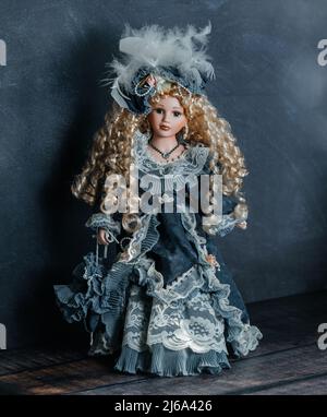 Erstaunlich realistische Vintage Puppe mit grünen Augen. Die Puppe in einem grünen Kleid mit Spitze gekleidet. Selektiver Fokus. Porzellan. Stockfoto