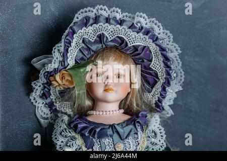 Erstaunlich realistische Vintage Puppe mit grünen Augen. Die Puppe in einem grünen Kleid mit Spitze gekleidet. Selektiver Fokus. Porzellan. Stockfoto