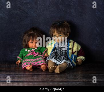 Erstaunlich realistische zwei Vintage Puppen: Mit blauen und braunen Augen.die Puppen sind in bunten Strickkleider gekleidet. Selektiver Fokus. Paar. Stockfoto