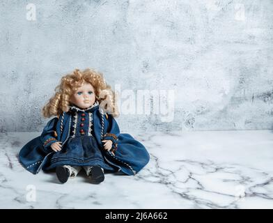 Erstaunlich realistische Vintage Puppe mit grünen Augen. Die Puppe in einem grünen Kleid mit Spitze gekleidet. Selektiver Fokus. Porzellan. Stockfoto