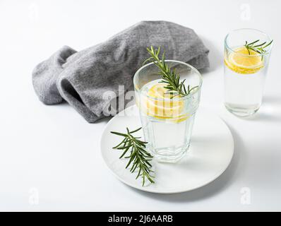 Zwei Gläser mit frischem Zitronenwasser oder hausgemachter Limonade mit Rosmarin auf weißem Hintergrund, Textil, Stockfoto, Konzept Stockfoto