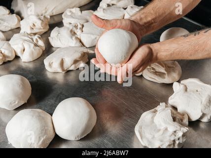 Pizzahersteller und Teigbällchen zum Backen auf Metalltisch Hintergrund Stockfoto