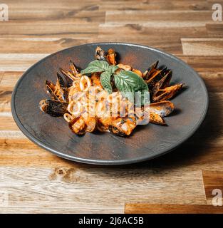 Italienische Spaghetti-Pasta mit Muscheln, Tomaten, Knoblauch, Olivenöl und Basilikum auf Holztisch, Meeresfrüchte-Cocktail, Restaurantkonzept, Stockfoto Stockfoto