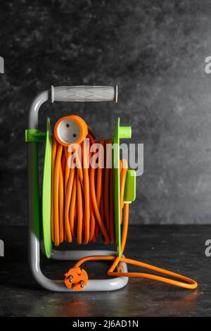 Verlängerung elektrische Kabelrolle auf dunklem Hintergrund, Nahaufnahme Stockfoto