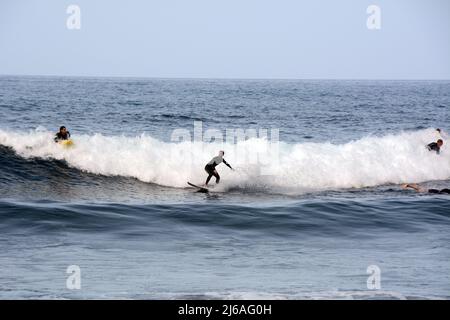 Ein männlicher Surfer im Nassanzug, der am Strand Playa del Socorro in Los Realejos, an der Nordküste von Teneriffa, Kanarische Inseln, Spanien, eine Welle surft. Stockfoto