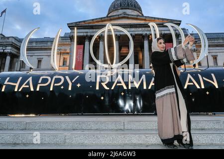 London, Großbritannien, 29.. April 2022. Eine junge Frau macht Selfies mit dem Schild „Happy Ramadan“ und der Nationalgalerie im Hintergrund. Das größte britische Open Iftar, das bz Ramadan Tent Project, bringt Menschen aus allen Gemeinden zusammen, um ein Iftar (Abendmahl) zu teilen, um während der letzten Woche des islamischen heiligen Monats Ramadan zu fasten. An der Veranstaltung nehmen Sadiq Khan, Bürgermeister von London, und rund 2.000 Mitglieder der Öffentlichkeit Teil. Kredit: Imageplotter/Alamy Live Nachrichten Stockfoto