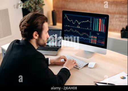 Investitionen, Handel an der Börse. Der erfolgreiche kaukasische männliche Trader-Investor, der den Kryptowährungsfinanzmarkt analysiert, schaut sich den Computer an, erarbeitet eine Krypto-Strategie und analysiert Risiken Stockfoto