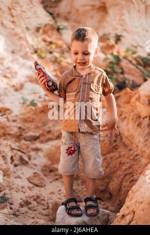 Ein glücklicher kleiner Junge hält eine Schreibmaschine in den Händen, lächelt und schaut nach unten Stockfoto