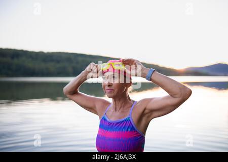 Porträt einer aktiven älteren Schwimmerin im Freien am See. Stockfoto