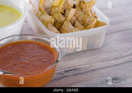 ' Ketupat & Asam Pedas Tetel' . Traditionelles festliches Gericht aus Reiskuchen mit mehreren Beilagen, das während der Eid-Feierlichkeiten im Volksmund serviert wird Stockfoto