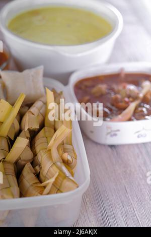 ' Ketupat & Asam Pedas Tetel' . Traditionelles festliches Gericht aus Reiskuchen mit mehreren Beilagen, das während der Eid-Feierlichkeiten im Volksmund serviert wird Stockfoto