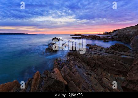 Geschnitzte malerische Sandsteinfelsen an der australischen Sapphire-Küste am Strand von Tathra mit Blick auf den Hafen von Tathra bei Sonnenaufgang. Stockfoto