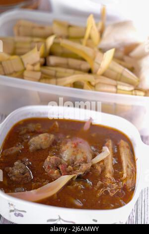 ' Ketupat & Asam Pedas Tetel' . Traditionelles festliches Gericht aus Reiskuchen mit mehreren Beilagen, das während der Eid-Feierlichkeiten im Volksmund serviert wird Stockfoto