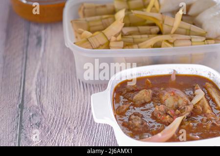 ' Ketupat & Asam Pedas Tetel' . Traditionelles festliches Gericht aus Reiskuchen mit mehreren Beilagen, das während der Eid-Feierlichkeiten im Volksmund serviert wird Stockfoto