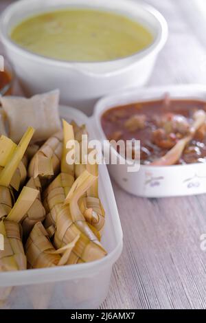 ' Ketupat & Asam Pedas Tetel' . Traditionelles festliches Gericht aus Reiskuchen mit mehreren Beilagen, das während der Eid-Feierlichkeiten im Volksmund serviert wird Stockfoto