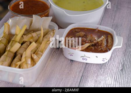 ' Ketupat & Asam Pedas Tetel' . Traditionelles festliches Gericht aus Reiskuchen mit mehreren Beilagen, das während der Eid-Feierlichkeiten im Volksmund serviert wird Stockfoto