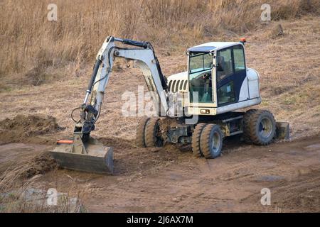 Erdbeweglicher Traktor, der Platz für den zukünftigen Bau des Hausfundaments vorbereitet. Nivellierung Boden für den Bau neuer Heimat. Stockfoto