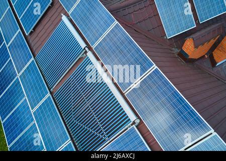 Photovoltaik-Paneele und Vakuum-Luft-Sonnenkollektoren für die Warmwasserbereitung und die Produktion von sauberem Strom auf dem Hausdach montiert. Produktion von Stockfoto