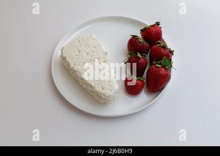 Quark mit frischen Erdbeeren auf weißem Teller. Stockfoto