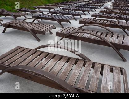 Reihe leerer Holzliegen am Strand. Stockfoto
