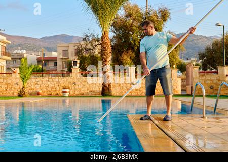 Mann, der den Außenpool putzt, schöne Aussicht auf die Natur im Hintergrund Stockfoto