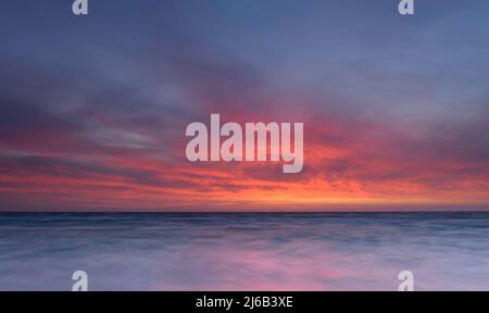 Wunderschöner Sonnenuntergang über dem Meer, der sich im Wasser spiegelt Stockfoto