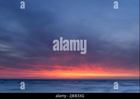 Wunderschöner Sonnenuntergang über dem Meer, der sich im Wasser spiegelt Stockfoto