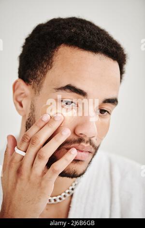 Hübscher gepflegter Mann mit Accessoires, die Patches auf sein sauberes Gesicht auftragen Stockfoto