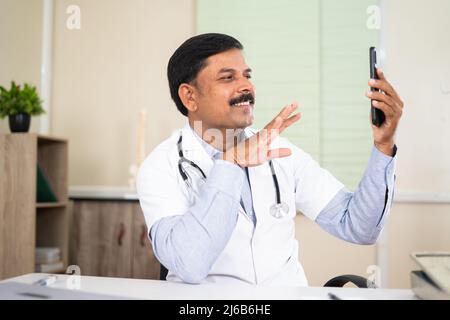 Arzt auf Videoanruf mit Patient auf Handy im Krankenhaus - Konzept der mhealth, visrutäre medizinische Beratung und Technologie Stockfoto