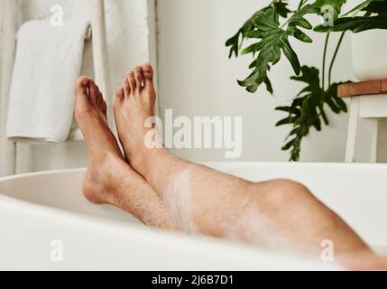 Nahaufnahme eines Mannes, der im Bad mit Schaum liegt und sich während des Spa-Eingriffs entspannt Stockfoto