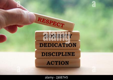 Business Concept Text auf Holzblöcken mit der Hand, die einen Holzblock hält - Respekt, Ehrlichkeit, Hingabe, Disziplin und Handeln. Stockfoto