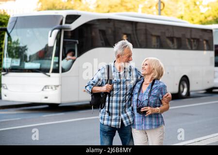 Gerne älteres Paar Touristen umarmen vor der Touristenbus Stockfoto
