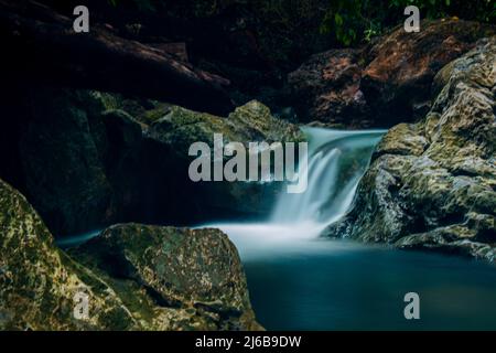 Wasser fließt über die Felsen. Blaues und klares Wasser in einem Bergfluss. Aceh, Indonesien Stockfoto