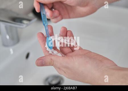 Waschen mit Zahnbürste und Seife kieferorthopädische unsichtbare Zahnspangen. Stockfoto