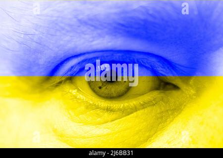 Menschliches Gesicht mit Flagge der Ukraine gemalt. Stockfoto