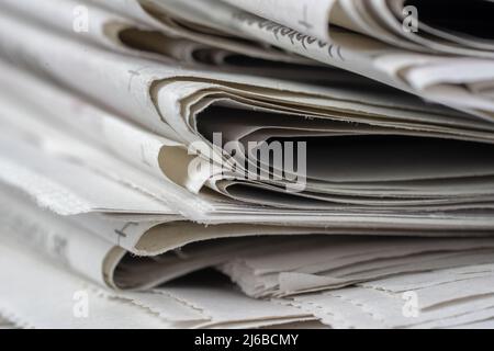 Makroaufnahme eines Stapels von Zeitungen. Die Zeitungen sind gefaltet und die Artikel sind nicht lesbar Stockfoto