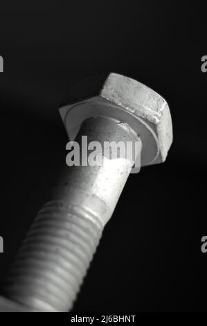 Verzinktes Stahlmetall mit metrischem Bolzen, isoliert auf schwarzem Hintergrund Stockfoto