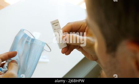 Man-Check-Ergebnis des Covid-19-Schnellantigen-Testkits zu Hause, negativ, erholt Stockfoto