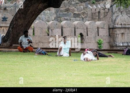 Vellore, Tamil Nadu, Indien - 2018. September: Eine Gruppe indischer Männer, die sich auf dem grünen Gras des Parks Vellore Fort ausruhen und entspannen. Stockfoto