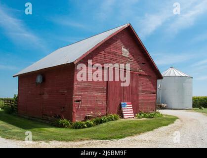 Eine kleine alte rote Scheune mit US-Flagge davor. Sehr ländlich und sehr malerisch. Stockfoto