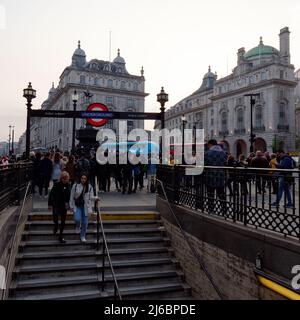 London, Greater London, England, April 23 2022: Piccadilly Circus von der U-Bahnstation aus gesehen, während sich Massen versammeln, um einen Straßenakt und ein Rot- und ein B zu beobachten Stockfoto