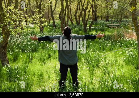 Rückschuss von langhaarigen Mann mit offenen Händen in Wald isoliert. Stockfoto