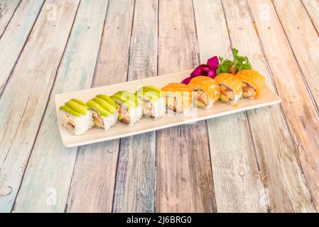 Gemischtes Uramaki Sushi-Tablett mit norwegischem Lachs mit frischem Käse, Avocado, Nori-Algen, Surimi auf Holztisch Stockfoto