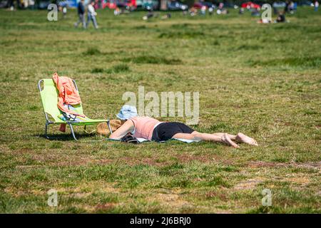 London, 30. April 2022. Eine Frau, die auf Wimbledon Common den Sonnenschein einweicht, da das sonnige Wetter über das Feiertagswochenende prognostiziert wird. Kredit: amer ghazzal/Alamy Live Nachrichten Stockfoto