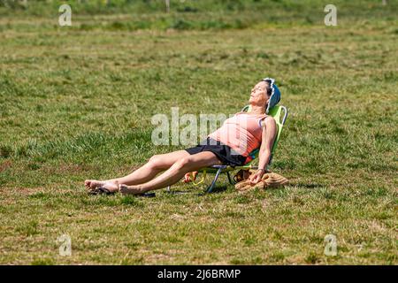London, 30. April 2022. Eine Frau, die auf Wimbledon Common den Sonnenschein einweicht, da das sonnige Wetter über das Feiertagswochenende prognostiziert wird. Kredit: amer ghazzal/Alamy Live Nachrichten Stockfoto
