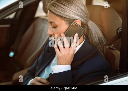 Reife asiatische Geschäftsfrau sprechen auf Handy, während Auto fahren Stockfoto