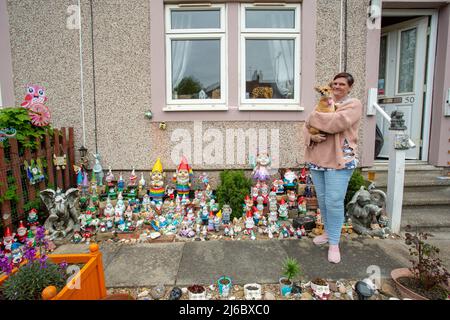 Nicola mit ihrem Hund, der vor ihrer Sammlung von Gartengnomen vor einem Reihenhaus in Luset, Wakefield, West Yorkshire, England, posiert. Stockfoto