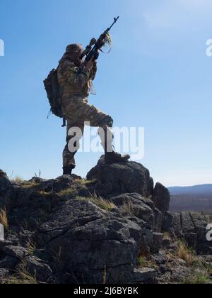 Professionelle Spezialeinheiten Scharfschütze während einer Spezialoperation - er zielt auf den Feind. Ein Hinterhalt in den Bergen. Konzept der modernen militärischen Operationen und Stockfoto
