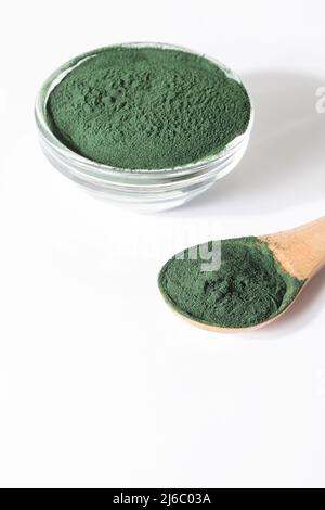 Natürliche Zusatzstoffe und Superfood. Grünes Spirulina Algenpulver im Glas mit Holzlöffel auf weißem Hintergrund. Gesundes Lifestyle-Konzept. Bio-Lebensmittel Stockfoto